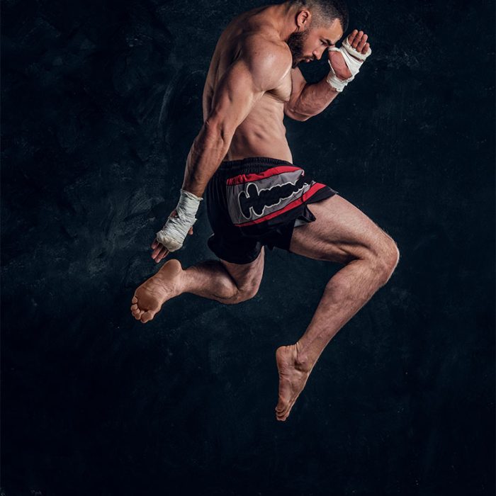 focused-physically-fit-man-is-jumping-making-illusion-flight-before-punch-dark-studio